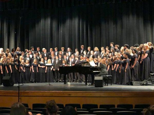 HTHS Choirs standing on stage at a concert HTHS Choirs standing on stage at a concert